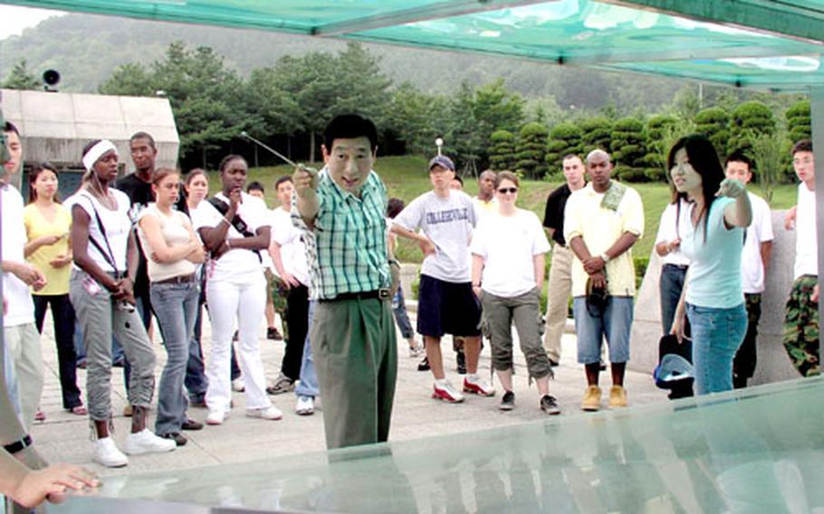 At Dabudong battlefield monument near Waegwan, South Korea, soldiers and college students listen as a monument official uses a glass-encased model of the battle area to explain how South Korean and U.S. troops prevented North Korean invasion forces from breaking through to Daegu in 1950, in the Korean War's early months.