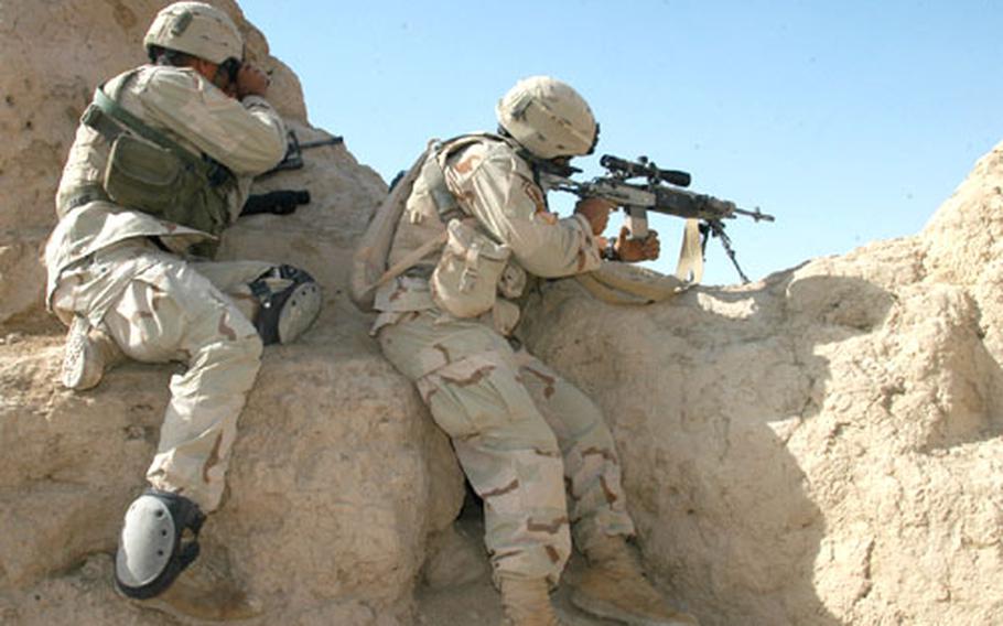 Spc. Archie Moore, with the M-14 rifle, and his spotter, Spc. Mick Sleik, watch a handful of Afghan men near a building as other members of Company B, 2nd Battalion (Airborne), 503rd Infantry Regiment, clear a village and compound of Taliban fighters.