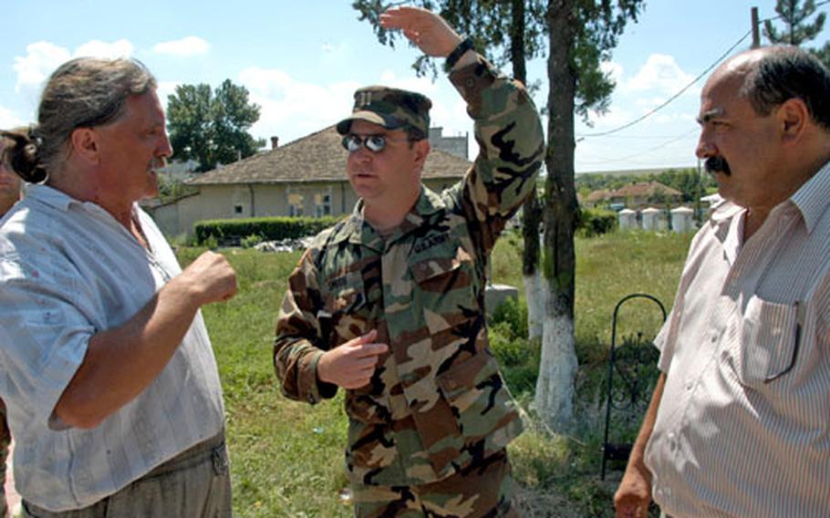Capt. Todd Smith, of the Texas National Guard’s 36th Infantry Division, explains to Mayor Soare Ion of Cogealac, Romania, right, and local painter Ioan Borloveanu that any decision to build a U.S. base in Romania would occur at a higher level of command.