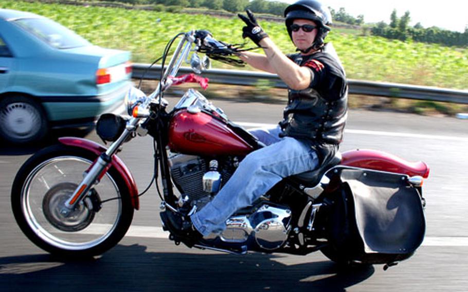 Petty Officer 2nd Class Ben “Whiner” Simons, acting president of the Naples, Italy-based Breakaway Motorcycle Club, flashes a peace sign as he and fellow bikers headed out July 23 for the biker rally in the Matese Mountains in southern Italy.