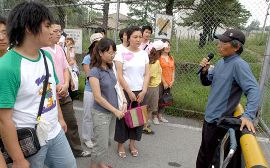 South Korean photographer Lee Yongnam addresses a group of protesters Tuesday at the main gate of Camp Stanton, near South Korea’s Demilitarized Zone. About 90 protesters rode by bus to several bases near the DMZ that the Army vacated in 2004. They said they wished to draw attention to U.S. military facilities’ economic impact on an area.