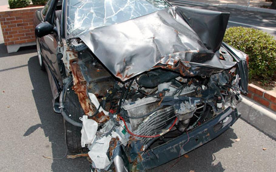 A Japanese-built compact sits at the main gate of Sasebo Naval Base, Japan. Officials plan to leave the twisted mass of metal, glass and hard plastic on display for several weeks in hopes it reminds or re-educates drivers about the importance of safe driving.