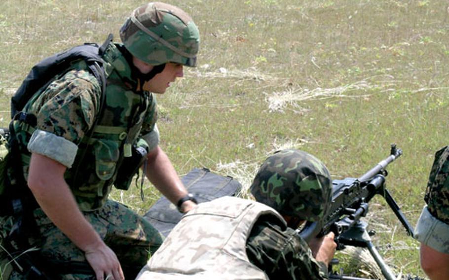 Sgt. Matthew P. Dannenberger, Company F, 2nd Battalion, 23rd Marine Regiment, assists a Ukrainian soldier in firing the M-240G machine gun during exercises last week at the Stary Krem Training Center in the Ukraine.
