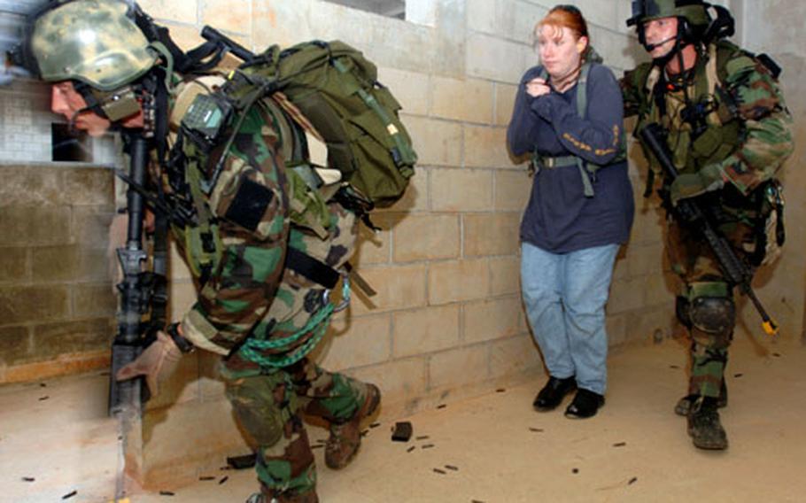 Tech. Sgt. Brandon Casteel, left, and Senior Airman Sean Cole, right, both pararescue personnel from the 31st Rescue Squadron, Kadena Air Base, Japan, "rescue" 1st Lt. Julie Reaser, also from the 31st RQS, at Combat Town training area.