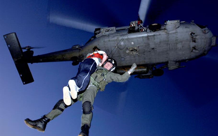 Airman 1st Class Mandy Fessel from the 18th Medical Support Squadron, Kadena Air Base, Japan, is extracted by a Navy HH-60G helicopter from the aircraft carrier USS Kitty Hawk during a non-combatant evacuation exercise at Combat Town training area.