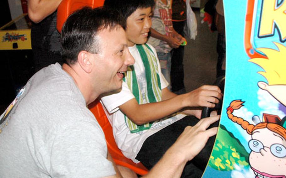 Chief Petty Officer Bill Covington, from the operations aerology division of the USS Essex, plays a video game Friday afternoon at Sasebo Naval Base’s Bowling Center with a youngster from the Koyo Ryou Childrens’ Home in nearby Omura City.