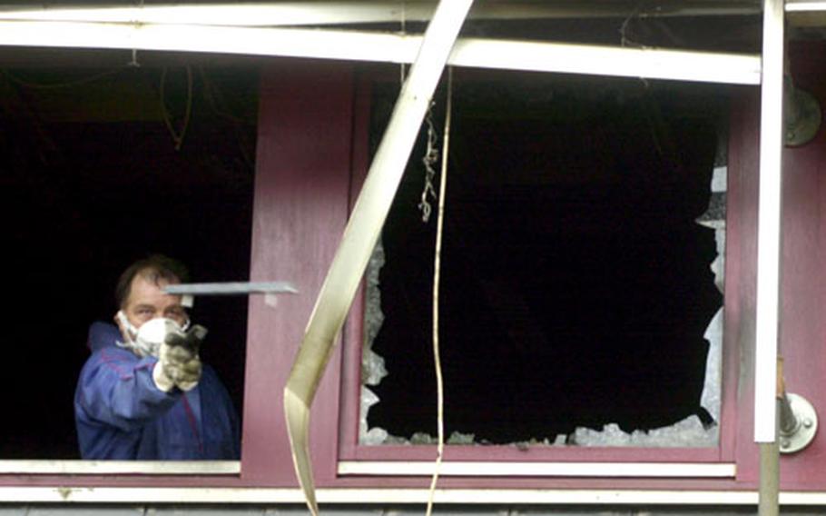 A German salvage worker tosses scrap out of the burned out interior of Baumholder’s city goverment building.