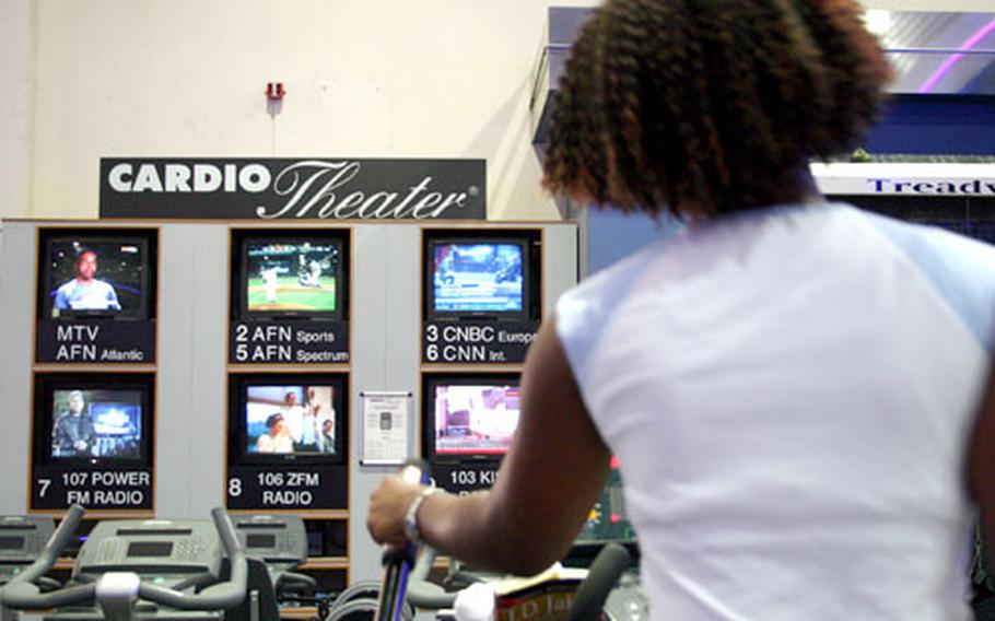 Petty Officer 3rd Class Nicole Niter watches the American Forces Network as she works out at the Fit Zone recently at Naval Support Activity Naples, Italy. AFN television is set up in the gym's cardio center.