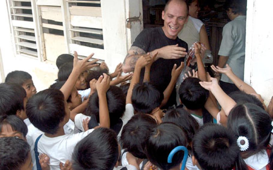 Petty Officer 1st Class Dean Marzano, damage control training team coordinator aboard the USS Safeguard from Sasebo, attempts to hand out candy and treats to children at the Iram Elementary School during a community-relations project near Subic Bay, Philippines.