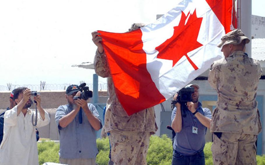 Soldiers from the Canadian Army prepare to raise the nation's flag over the Kandahar Provincial Reconstruction Team Tuesday as members of the Canadian and Afghan media videotape and photograph the event.