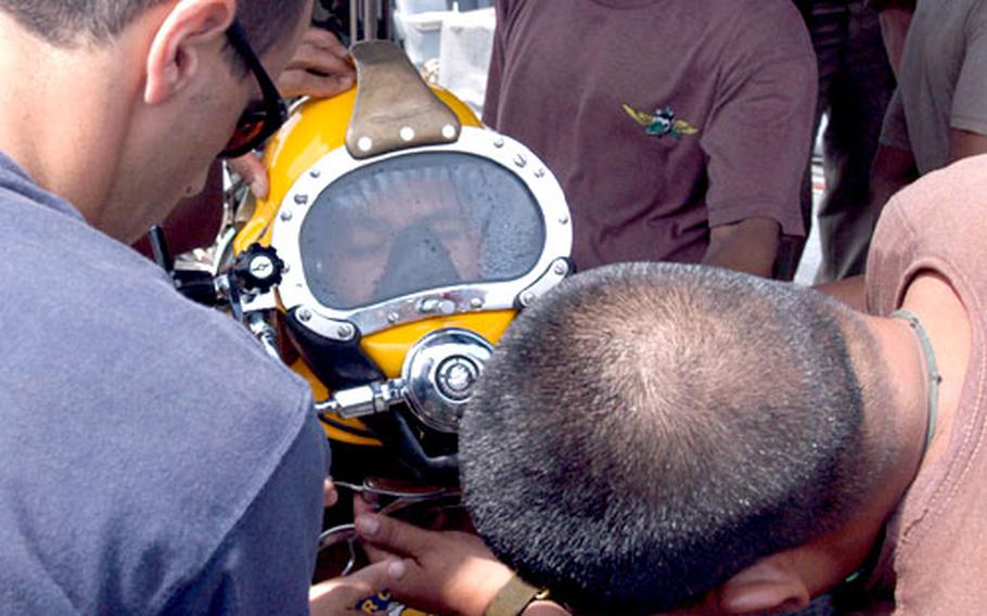 Dive tenders get a Philippine diver ready for the Mark 21 hard-hat dive rig, a U.S. Navy system aboard the USS Safeguard that allows longer dives by providing a ship-based air feed, as opposed to a self-contained breathing system.
