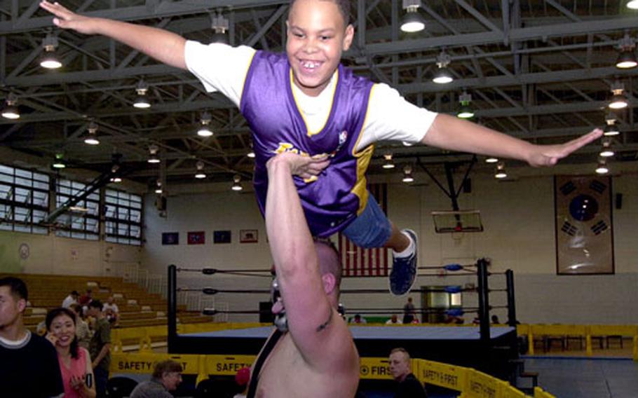 Krash hoists 8-year-old Joshua Tyson over his head for a photo before the wrestling matches Saturday night at Yongsan Garrison’s Collier Field House.