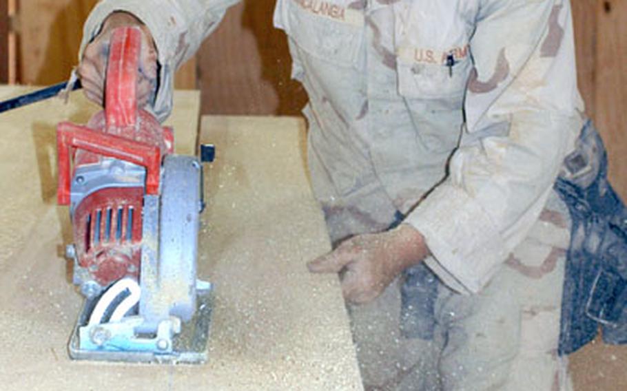 Spc. Gian Francalangia, Company A, 94th Engineer Combat Battalion (Heavy) cuts a sheet of plywood Friday at Command Outpost Rawah. Francalangia was working on the Morale, Welfare and Recreation building, which will house an Internet cafe for soldiers based at the outpost.