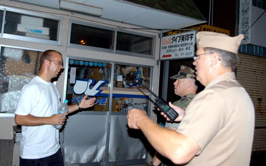 Capt. Wayne Radloff, NAF Misawa commander, and Petty Officer 1st Class Thomas Perkins, a master-at-arms, stop to give directions to a civilian.