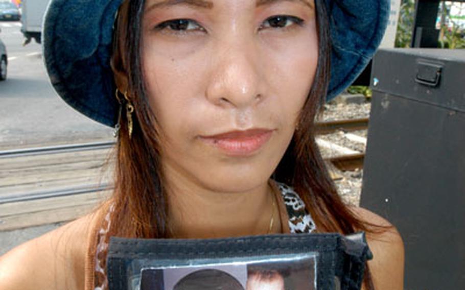 Ederlyn Gerrard holds a picture of her baby, Monica, outside the front gate of Camp Red Cloud. Ederlyn has accused her husband, Army Sgt. Thomas Gerrard, of improperly taking the infant to the United States.