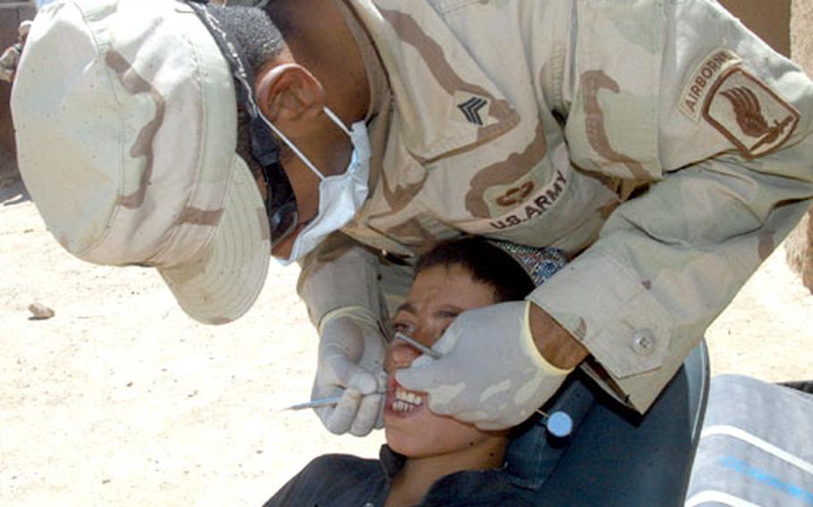 Sgt. Julio Carmona, a dental technician with the Vicenza, Italy-based Company C, 173rd Support Battalion, works on the teeth of an Afghan boy in Baghran, Afghanistan.
