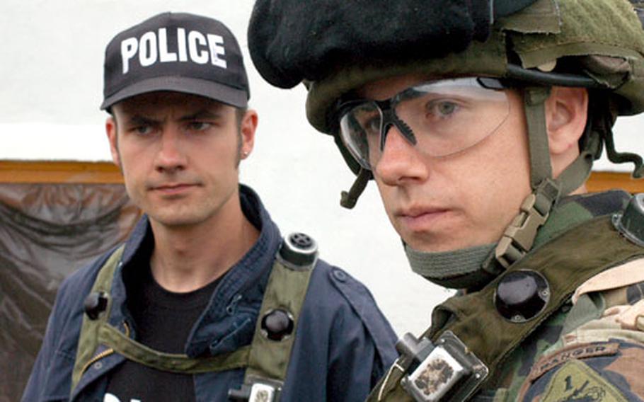 First Lt. Patrick Fagan, right, motions to his troops in Company A of the 1st Battalion, 35th Armored Regiment while talking to an “Iraqi policeman” at the Hohenfels training area Wednesday. As part of his unit’s preparation to return to Iraq this fall, Fagan’s unit was out hunting for a vehicle used in a fictional kidnapping of a U.S. citizen.