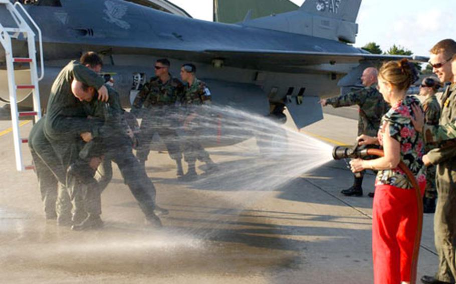 Crewmembers attempt to hold down Brig. Gen. William Rew, 35th Fighter Wing commander, while his wife, Christy, hoses him with water after his final flight at Misawa Air Base, Japan, on Wednesday.