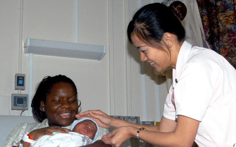 Hokubu Nursing School student Nanako Matayoshi hands 4-day-old Jasmyn Monet to her mother, Deniece Thomas, at U.S. Naval Hospital Okinawa earlier this month. Matayoshi is one of two students participating in a three-week cultural exchange to learn more about American nursing.