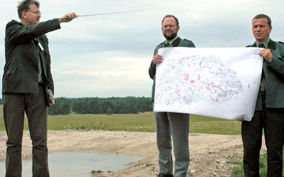 Alexander Patt from the German Federal Agency for Real Estate Management, left, points Thursday to an area of the Grafenwöhr training area where foresters have performed erosion control to prevent parts of the local landscape from washing away.