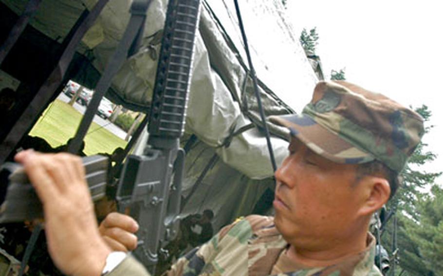 15th Company, Korean Service Corps assessor Choe Hyo-sop demonstrates the correct way to load a magazine into an M-16 rifle. KSC members are civilians and do not carry weapons, but must know how to operate them in time of war.