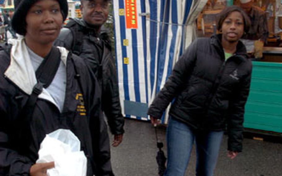 From left, Staff Sgt. Vanessa Marks, Staff Sgt. Donald Dixon, and Spc. Kimberly Coleman, all Army reservists from the 1015th Maintenance Company of Fort Gillem, Ga., stroll through the Oktoberfest midway during the festival’s rainy opening hours on Saturday in Munich, Germany.