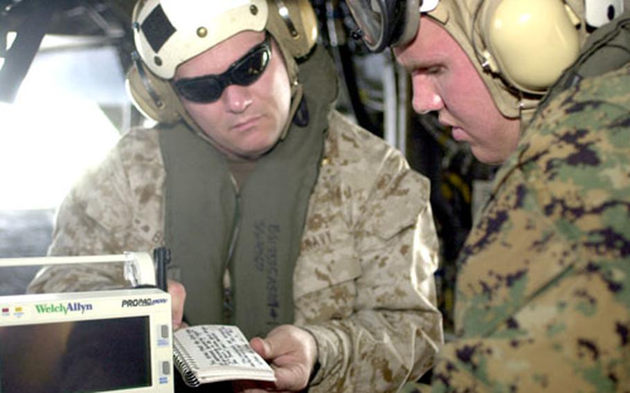 Petty Officer 3rd Class Graham Suchman, right, a corpsman with 3rd Medical Battalion, is quizzed by Navy Lt. Ron Bolen, an En Route Care instructor from Camp Lejeune, N.C., during a flight around Okinawa.