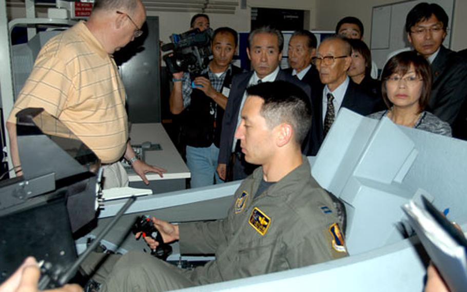 Capt. Kevin Jones, a pilot with the 35th Fighter Wing at Misawa Air Base, Japan, demonstrates a flying procedure in an F-16 simulator for Japanese government and city officials Thursday.