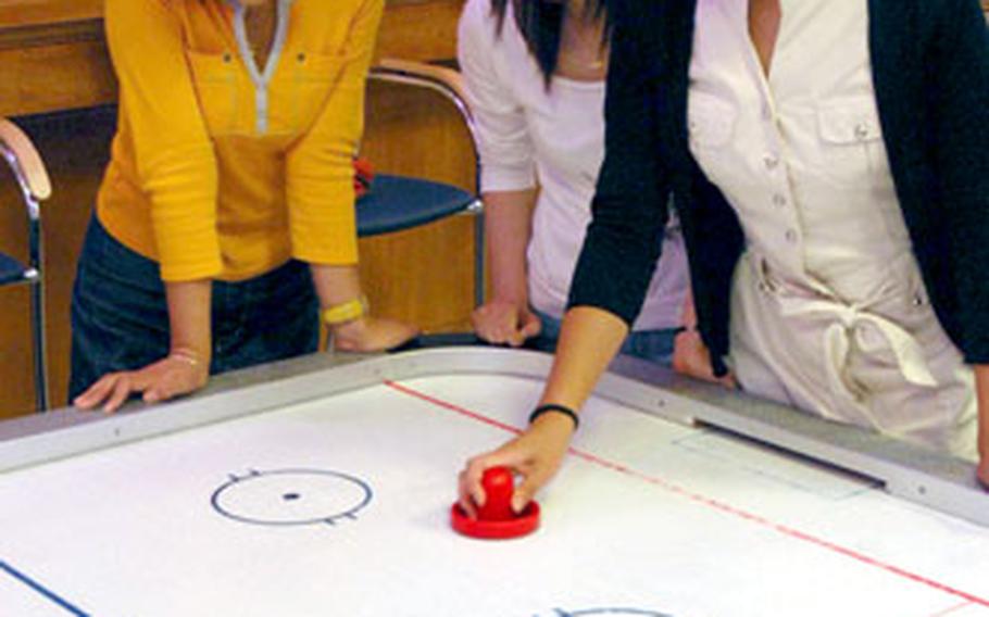 Students from Keimyung University, South Korea, try their hand at air hockey during a visit to the Community Activity Center on Camp Walker last month. About 30 students from the university visited the Area IV Support Activity in Daegu and were given a tour of the installation.