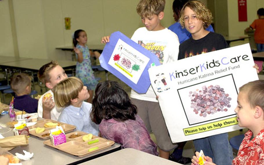 Sixth-grader Roy Beecher, right, and fifth-grader Matt Vohr carry signs asking for hurricane relief donations in Kinser Elementary School’s cafeteria Friday at Camp Kinser, Okinawa. Students at the school have collected more than $1,200 for the relief fund.