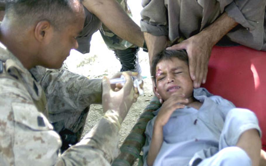 U.S. Navy Corpsman Eric Eberdong flushes out the head wound of an Afghan child Monday in the eastern Afghanistan village of Watapoor. Eberdong was attached to 3rd Platoon, Company E, 2nd Battalion, 3rd Marine Regiment, 3rd Marine Division for a five-day patrol. The child fell while running.