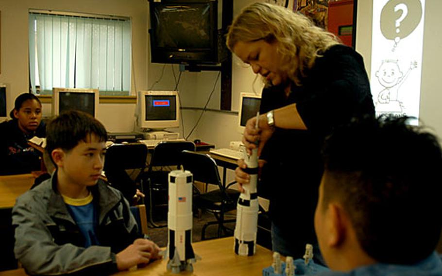 Etan Bard, 13, watches as teacher Romy Kerstetter uses a model to show how the rockets attached to the Apollo missions propelled astronauts into space.