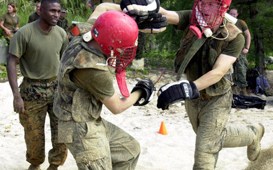 Lance Cpl. Randy Anderson, a military police patrolman from MCAS Futenma, makes a "killing blow" to his opponent's head with a rubber knife during hand-to-hand combat training on Camp Schwab Tuesday. Staff Sgt. Antonio Mitchell, left, watch commander at MCAS Futenma, supervises for safety.