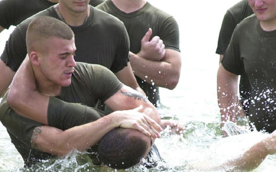 Lance Cpl. Roberto Soares, military police patrol supervisor on Camp Foster, "chokes out" Lance Cpl. Timothy Richardson, a patrolman at MCAS Futenma, during a grappling training session in the water just off the beach of Camp Schwab Tuesday.