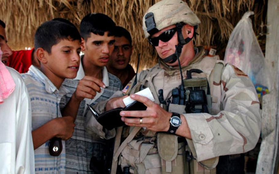 Locals in Mushada, Iraq, look at family photos from Capt. Gregory Spencer. Despite being open in their criticisms of Americans, many Iraqis have a playful relationship with U.S. soldiers.