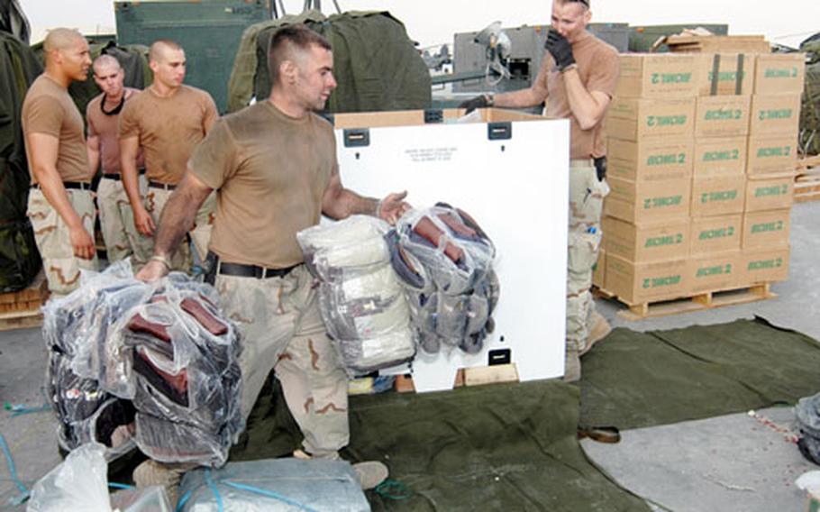 Spc. Bryan Jackson, front, and other parachute riggers with Logistical Task Force 307, based out of Bagram Air Base, Afghanistan, load pallets with humanitarian supplies this week.