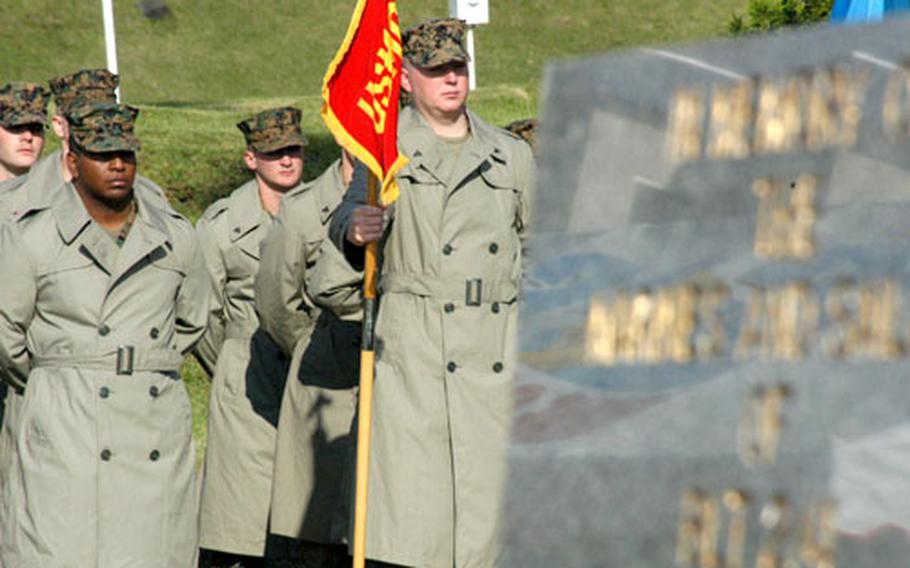 Marines from Camp Fuji's Combined Arms Training Center stand solemnly near the fire memorial marker at Wednesday's annual ceremony at the base flagpole. The observance marked the Oct. 19, 1979, blaze that killed 13 Marines and injured dozens more.