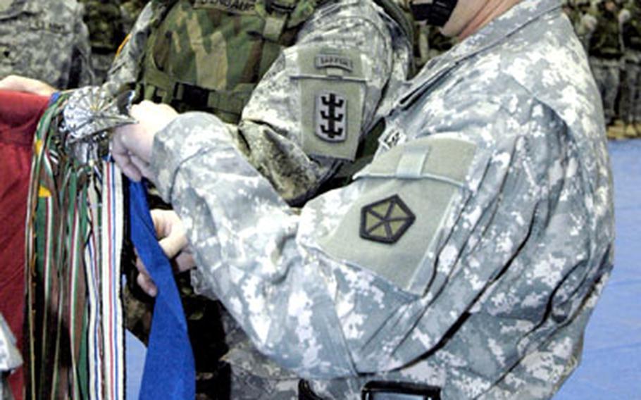 Command Sgt. Maj. Terry Defenbaugh, 54th Engineer Battalion, left, helps Brig. Gen. Daniel A. Hahn, V Corps deputy commander, place the Presidential Unit Citation on the 54th Engineers' guidon Friday during a deployment ceremony on Warner Barracks in Bamberg, Germany.