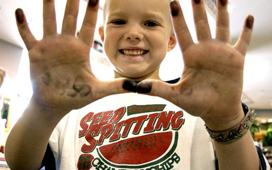 Harrison Read, 6, shows off his ink-stained fingers after recording his fingerprints on a child identification and safety kit on Thursday at the Marine Corps Air Station Iwakuni, Japan, Marine Corps Exchange.