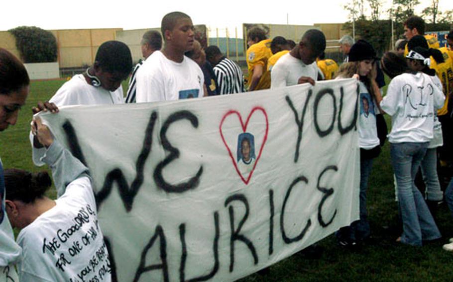 James Long III, second from left behind banner, and friends observe a moment of silence for James’ 12-year-old brother, Maurice, before Saturday’s homecoming football game between Heidelberg and Wiesbaden high schools. Maurice Long was killed Wednesday in an accident during Heidelberg High School’s homecoming parade.