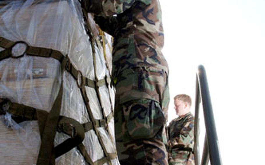 Timothy Stedelin, foreground, and Roy Biddle, senior airmen serving as air transportation specialists with Yokota Air Base’s 730th Air Mobility Squadron, check the straps of cargo pallets loaded with relief supplies bound for Pakistan.