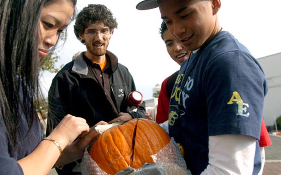 Yoko James and Jener Delos Santos show Nile C. Kinnick physics teacher Ryan Goodfellow the injuries their pumpkin sustained during a 65-foot drop Monday.