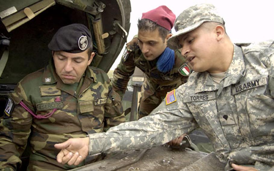 Spc. Juan Torres of 1st Squadron, 1st Cavalry Regiment, shows Italian Warrant Officer Vinoenz Blotta, in hatch, and another unnamed soldier, the controls of an M3A2 Bradley Armored Fighting Vehicle during Exercise Urgent Quest on England's Salisbury Plain.