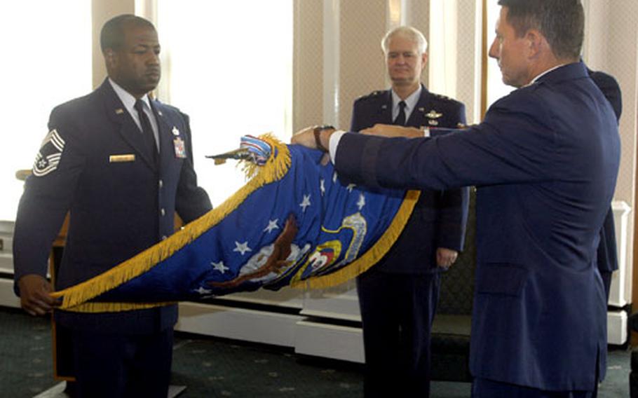 Maj. Gen. Michael Gould rolls up the 3rd Air Force flag Tuesday at RAF Mildenhall as deputy U.S. Air Forces in Europe commander Lt. Gen. Rod Bishop watches. Holding the flag as Gould rolls it is Chief Master Sgt. Derrick M. Candler.