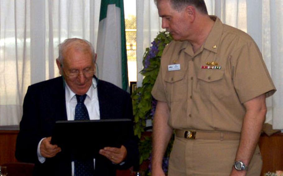 Capt. Philip Valenti, Fleet Industrial Supply Center Sigonella commanding officer, presents Sam Barbagallo with an honorary ownership plaque during Barbagallo’s retirement ceremony Oct. 28. Barbagallo worked at the base for more than 40 years.