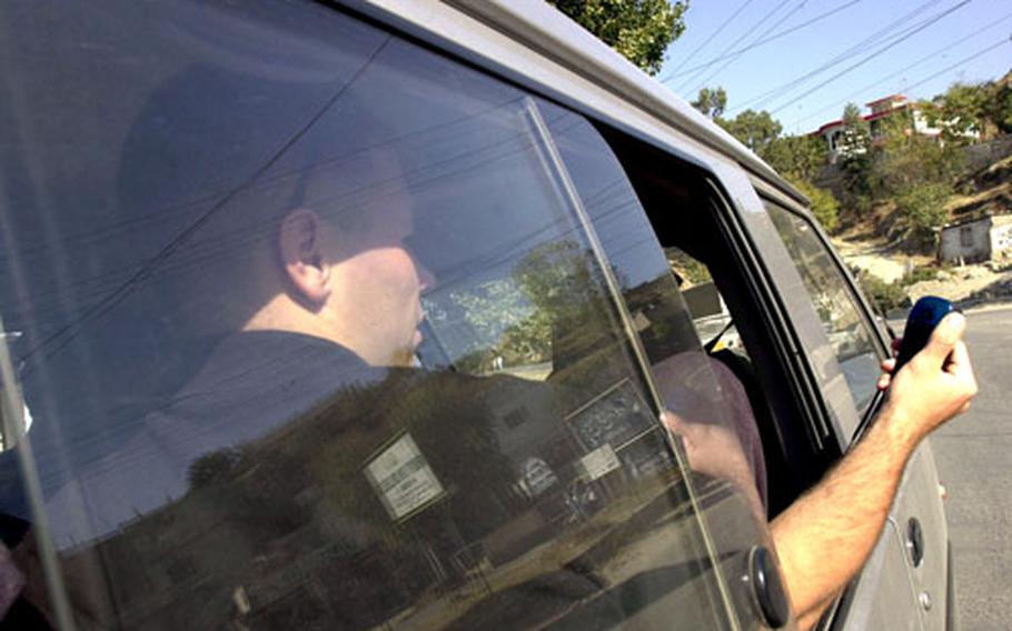 Marine 1st Lt. Stephen Kopach holds a Global Positioning System out the window of the van he rode in from Islamabad to Shinkiari, Pakistan, while mapping out the route the deploying unit from III Marine Expeditionary Force from Okinawa will be taking when they arrive here.
