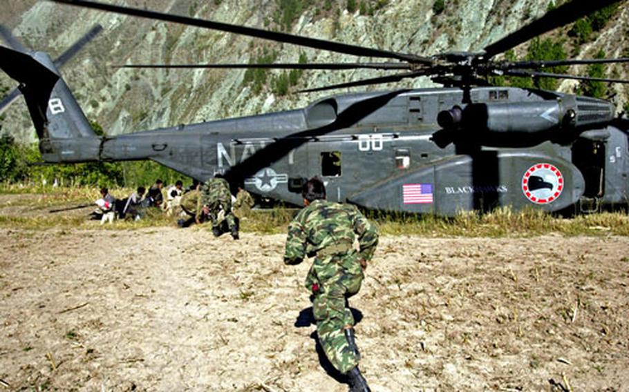 Pakistani soldiers run to a U.S. Navy MH-53 that landed Sunday to deliver relief supplies to the earthquake effected village of Paras, Pakistan.