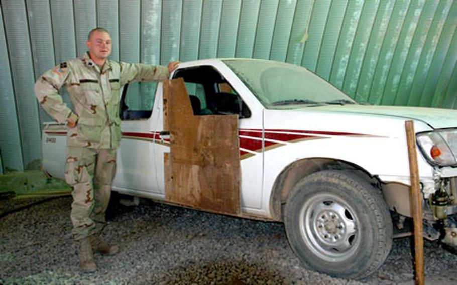 Sgt. Gordon Truett stands next to an Iraqi Army pick-up truck that he is using in designing vehicle armor that could help protect the local forces from roadside bombs.