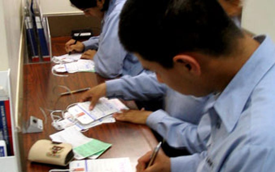 Sailors fill out paperwork to send packages in the mail Monday at the Sasebo Naval Base U.S. Post Office. Postal officials have recommended deadlines to make sure letters, cards and packages reach the United States in time for Christmas.