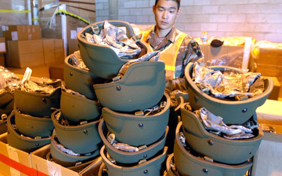 Cpl. Choi Sung-bae, 23, of Seoul, a Korean augmentee to the U.S. Army serving with 1st Battalion, 72nd Armored Regiment, prepares to fit soldiers with new Kevlar helmets at Camp Castle on Tuesday.